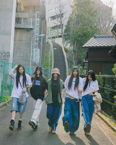 four girls are walking down the street together