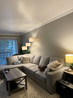 a living room with a couch, table and lamp on the floor in front of a window