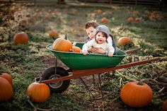 two children in a wheelbarrow with pumpkins