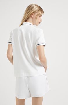 The comfortable-looking cotton interlock fabric is characterized by a soft and compact hand. Ribbed collar with button opening White Polo Shirt With Ribbed Collar For Work, Elegant White Polo Shirt With Ribbed Collar, Classic White Polo Shirt With Contrast Collar, White Cotton Polo Shirt With Ribbed Collar, White Sporty Polo Shirt With Collared Neckline, White Collared Polo Shirt, White Tops With Ribbed Collared Neckline, White Polo Shirt With Striped Collar For Workwear, Elegant White Polo Shirt For Work