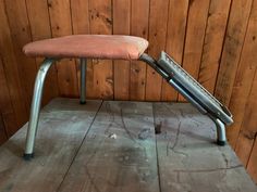 a chair with a foot rest on top of it in front of a wooden wall