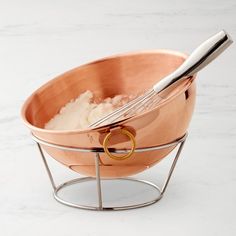 a large metal bowl with a whisk in it on a white counter top