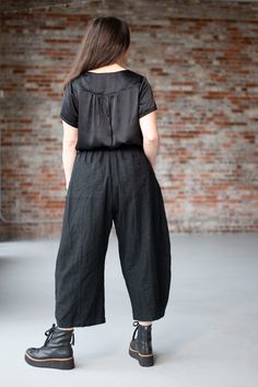 a woman standing in front of a brick wall with her back turned to the camera