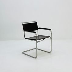 a black leather chair sitting on top of a white floor next to a metal frame