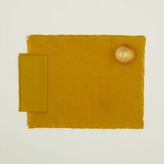 a yellow piece of cloth with a button on the side and a white square in the middle