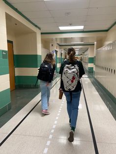 two girls walking down a hallway with backpacks