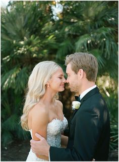 a bride and groom standing together in front of palm trees