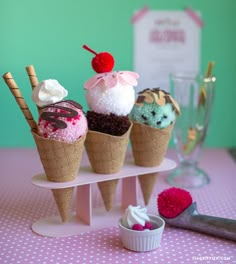 three ice cream cones with different toppings are on a pink and white tablecloth