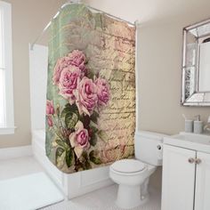 a white toilet sitting next to a bathroom sink under a shower curtain with pink roses on it