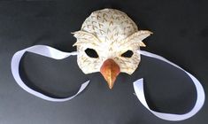 a mask with an eagle's head on it and white ribbon around the mouth