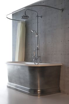 a bathroom with a tub and shower head on the wall, next to a curtained window