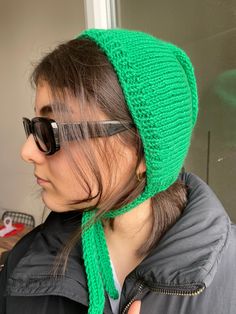 a woman wearing sunglasses and a green knitted hat