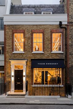 a brick building with three windows on the front and one door open to show clothes