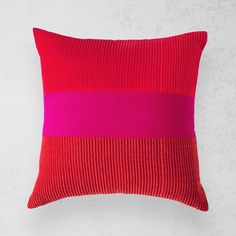 a red and pink pillow sitting on top of a white wall