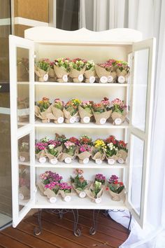 a shelf filled with lots of flowers on top of a wooden floor