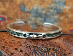 925 Sterling Silver Horse Hair Cuff Bracelet with snaffle bit centerpiece made with your horse's hair as a keepsake or we can make it with our stock horse hair.   Add engraving to your Pendant:  https://blueeyesdesignshb.etsy.com/listing/1769925811 Add a Custom Engraved Wood Gift Box: https://blueeyesdesignshb.etsy.com/listing/1750883342 Can be made with a regular 3 strand braid or a fishtail braid.   925 Silver Cuff Bracelet with horseshoe - 55x40mm (small) or 60x45mm (medium), includes braided horse hair -- if you need  a larger size I can order it. See my other listings for horseshoe cuff, heart cuff, bar cuff or turquoise cuff bracelets with horsehair and made from Sterling Silver.  If you need a larger size (please message me and I can custom order a larger size).   See my other horse 3 Strand Braid, Wood Engraved Gifts, Stock Horse, Hair Cuff, Hair Keepsake, Wood Gift Box, Boot Bracelet, Snaffle Bit, Hair Cuffs