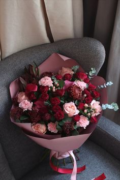 a bouquet of flowers sitting on top of a gray chair next to a red ribbon