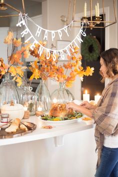 two women are standing in front of a table with food and candles on it that says happy thanksgiving