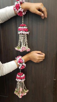 two hands are holding flowers and beads on a door