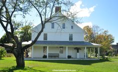 a large white house sitting on top of a lush green field next to a tree