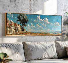 a painting hanging on the wall above a couch in front of a potted plant