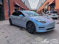 a blue electric car parked in front of a brick building