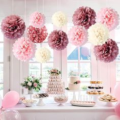 a table topped with lots of pink and white paper pom poms hanging from the ceiling