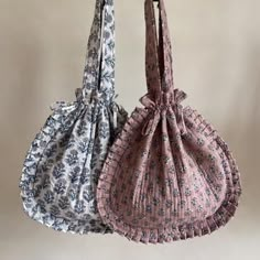 two purses hanging from hooks, one with a flowered design and the other with a bow tie