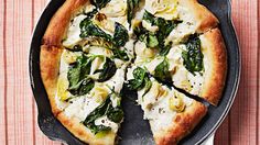 a pizza sitting on top of a pan covered in cheese and spinach