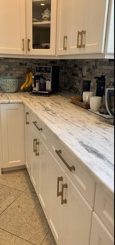 a kitchen with marble counter tops and white cabinets