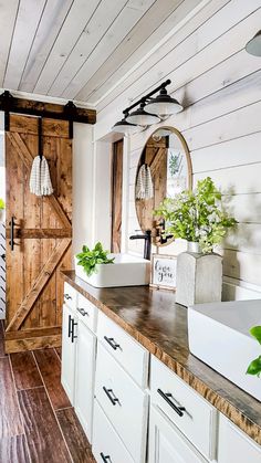 a bathroom with white cabinets and wooden doors on the wall, along with an open sink area