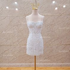 a white dress on a mannequin stand in front of a wall with lights