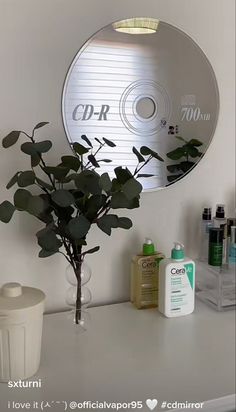 a white counter top topped with a vase filled with flowers next to a round mirror