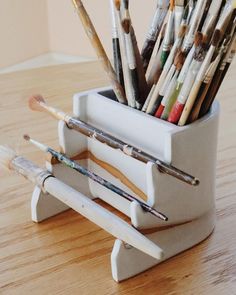 a cup filled with lots of different colored pencils on top of a wooden table