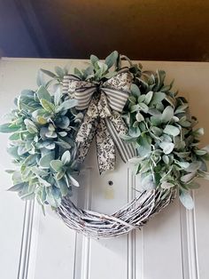 a wreath hanging on the front door is adorned with greenery and ribboned bow