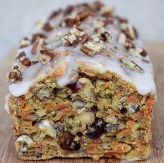 a close up of a pastry on a wooden surface with icing and nuts around it