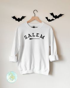 Salem Sweatshirt, Souvenir Shirt, Vacation Shirt, Witchy Gifts, Home Town Shirt, Salem Mass, Massachusetts, College Shirts, Salem Witches, Halloween Shirt, Witch Shirt, Halloween Shirts, Fall Sweatshirt, Fall T-Shirts This soft sweatshirt has a loose fit for a comfortable feel. With durable print, it will be a walking billboard for years to come. -Loose fit -50% Cotton; 50% Polyester (fibre content may vary for different colors) -Unisex - Fits true to size (see size chart for reference) - If you College Crew Neck Shirt With Screen Print, Crew Neck College Shirt With Screen Print, Relaxed Fit Crew Neck Shirt With Lettering, Crew Neck Shirt With Lettering In Relaxed Fit, White Cotton Shirt With Lettering, Salem Sweatshirt, Bachelorette Party Matching, Salem Witches, Salem Mass