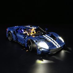 a lego model of a racing car in the dark with its lights on and it's hood up