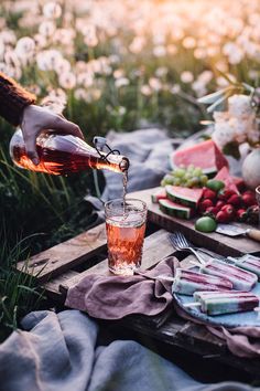 someone pouring tea into a glass on a picnic table