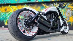 a white motorcycle parked in front of a graffiti covered wall