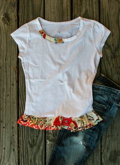 a t - shirt and jeans laying on top of a wooden floor