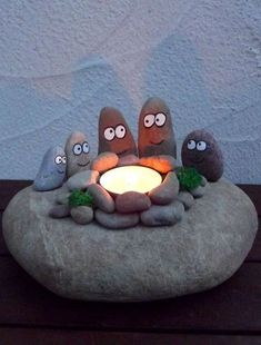 a rock with some rocks sitting on top of it next to a lit candle in the middle