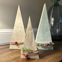 three small wooden christmas trees sitting on top of a table