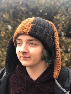 a young man wearing a knitted hat and scarf with ear piercings on his nose