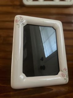 a small white frame sitting on top of a wooden table