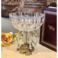 a crystal candle holder sitting on top of a table next to a book and flowers