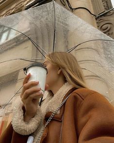 a woman holding an umbrella and drinking from a cup