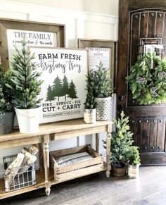 some potted plants are sitting on a table in front of a sign that says farm fresh christmas trees