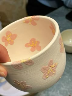 a person holding a bowl with flowers painted on it