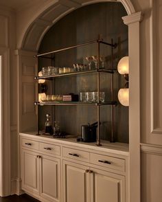 a kitchen with white cabinets and shelves filled with glasses